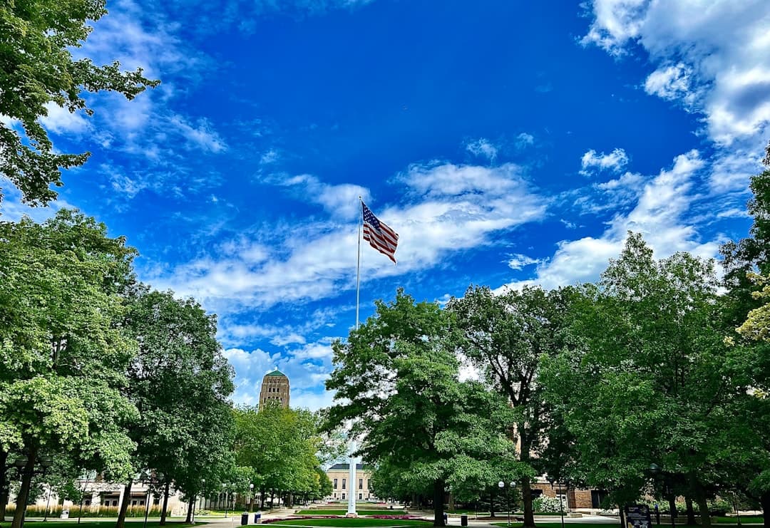 an american flag flying in the sky over a park