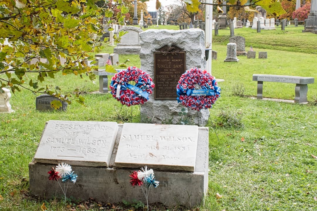 a couple of headstones sitting on top of a grass covered field