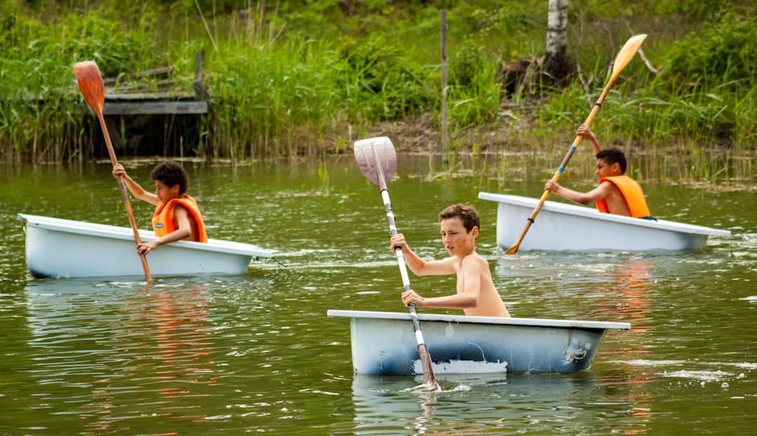 a group of young boys paddling canoes on a lake
