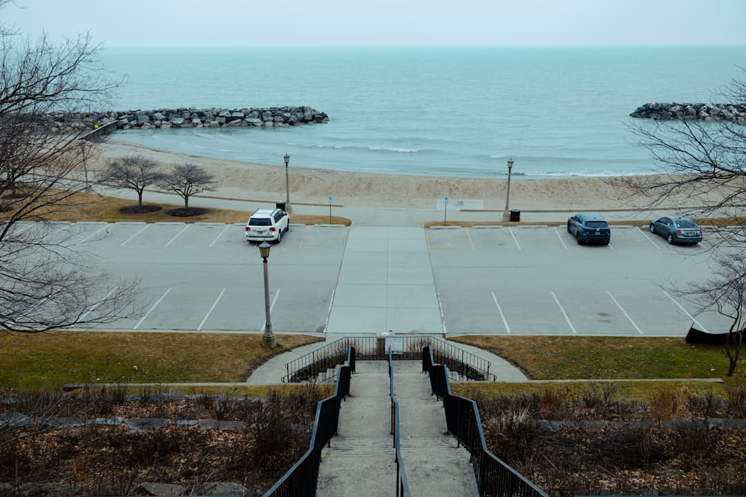 a parking lot next to the ocean with cars parked in it