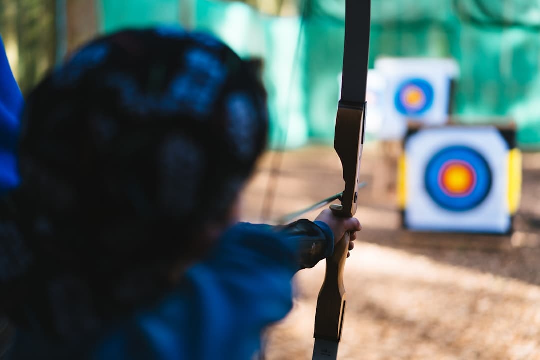 a woman is aiming a bow at a target