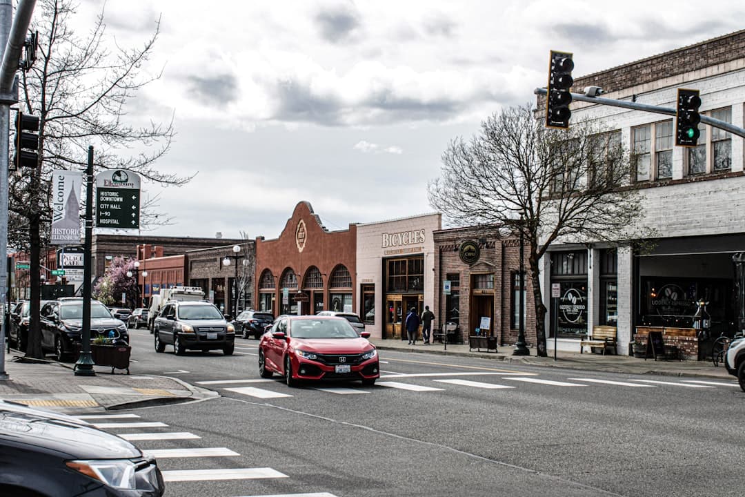 a red car driving down a street next to tall buildings