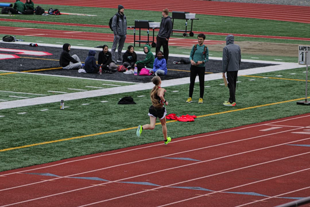 a woman running on a track with people watching